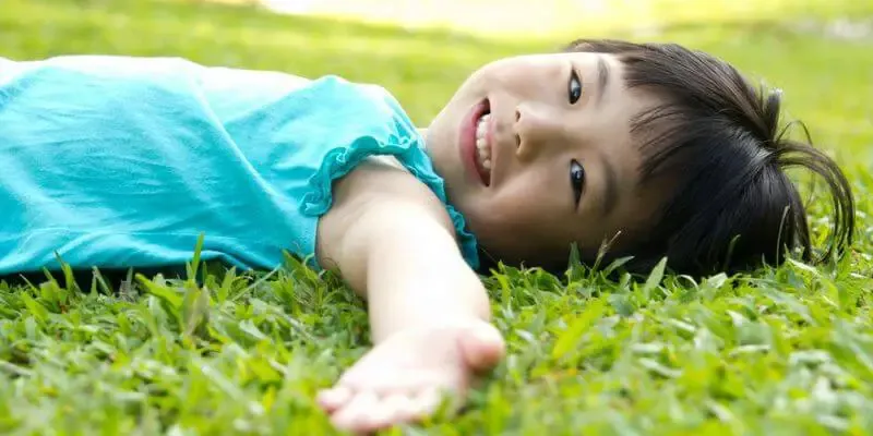 kid doing body scan in grass - Teaching Essential Mindfulness Practices and Skills body scan kids 