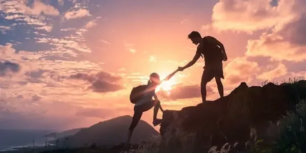 two people helping each other to climb up a mountain - self-acceptance 